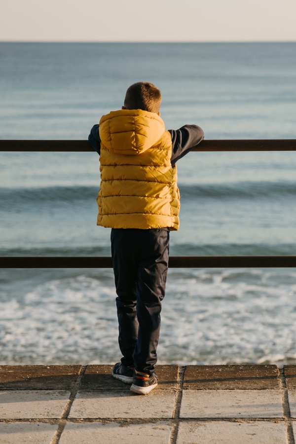 Child gazing out to sea near Worthing, evoking calm and quiet reflection